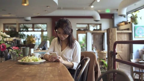 Push-in shot of woman using a smartphone in a restaurant Video stock 73291260