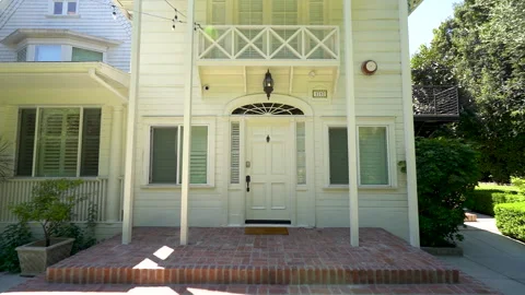 Push in toward the front door of a white wooden house with brick steps Stock Footage 345681736