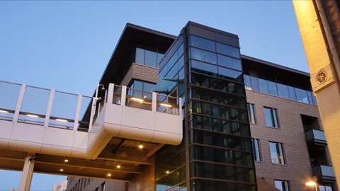 Push-in from underneath a pedestrian bridge and glass elevator Stock Footage 121816322