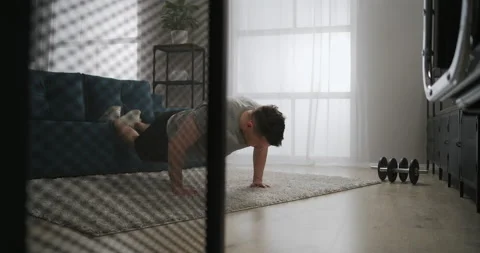 Push-ups workout in living room, adult sporty man is lifting his weight from Stock Footage 147939831