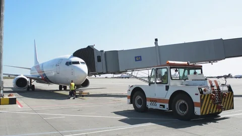 Pushback tractor stays in front of jet plane while crew walk around Stock Footage 94005181