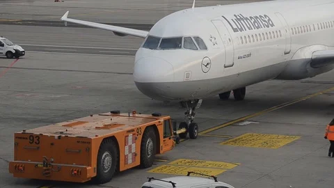 Pushback tractor tows Lufthansa Airbus A-321-200 aircraft away from gate Stock Footage 99086982