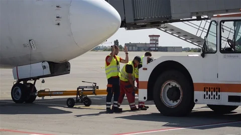 Pushback tug is connected to the big airplane by airport crew Stock Footage 94005232