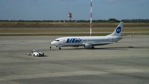Pushback tug drives away from white airplane Stock Footage 195933108