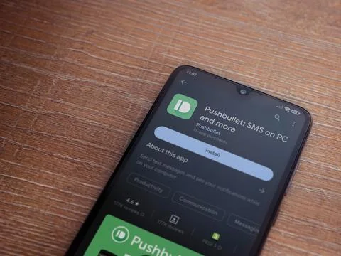 Pushbullet app play store page on smartphone on wooden background Stock Photos