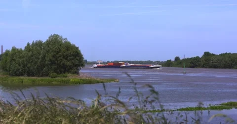 Pusher vessel with two loaded barges maneuvers upstream on inland waterway Stock Footage 64262600
