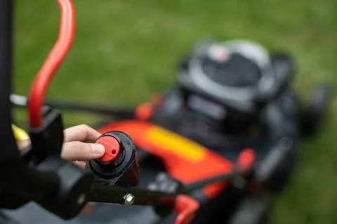 Pushes the start button on a lawn mower to cut grass. Photos