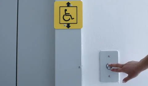 Pushing a button to call an elevator with a disabled person icon Stock Photos