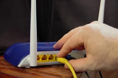 Pushing the cable into the wifi router for networking Stock Photos