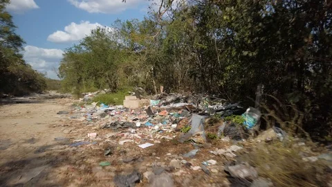 Pushing in fast on a dirt road lined with trash and garbage making it look like Video stock 128813099