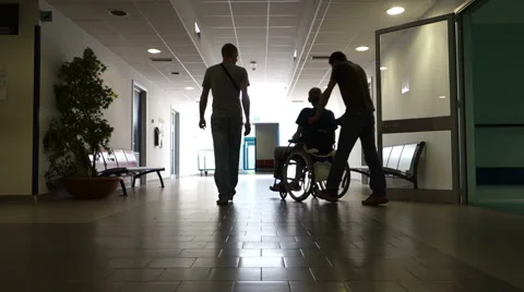 Pushing a man in a wheel chair, backlighting. Stock Footage
