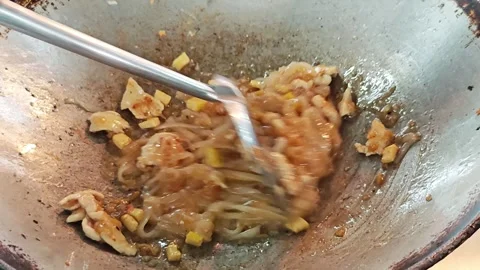 Pushing rice noodles to one side of a wok to make space close up. 스톡 동영상 339187774