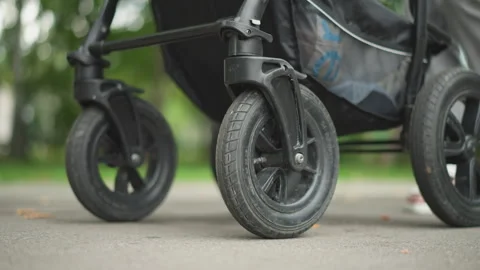 Pushing stroller outdoors. Caregiver strolls with child on pavement. Everyday Video stock 346380237