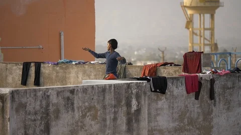 PUSHKAR, India - Indian boy flies kite on a roof surrounded by drying laundry Stock-Footage 87352147
