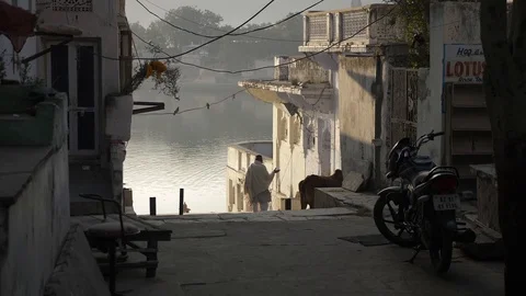 PUSHKAR, India - Indian man walks down steps to a ghat next to the Pushkar Lake Stock-Footage 87323901