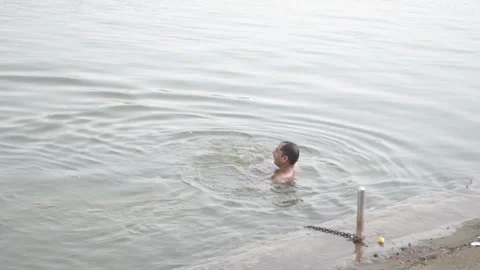 Pushkar, Rajasthan/ India - May 30 2020 : Middle aged man swimming in the lak Stock Footage 131361672