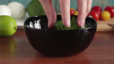 Put cherry tomatoes halves in to bowl with arugula salad leaves Stock Footage 105855213