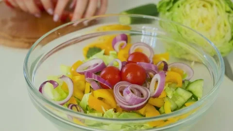 Put chopped cherry tomatoes into the glass bowl with cutted vegetables. Cooking Video stock 144243076
