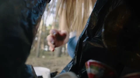 Put collected plastic and metal trash from the park into the black package Stock Footage 142143937