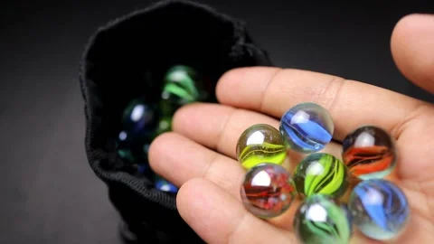 Put the colorful marbles into the bag container by hand Stock Footage 160309072