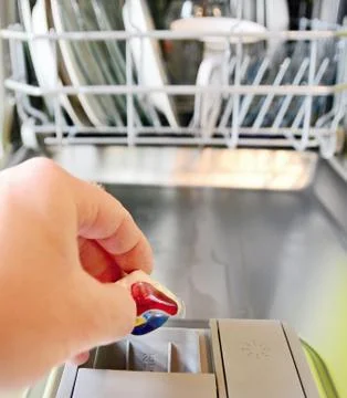 Put detergent tablet into dishwasher. Fotos Stock