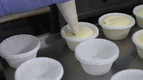 Put the dough into paper cups. Hand pouring cake dough into muffin tray Stockbeeldmateriaal 73811841