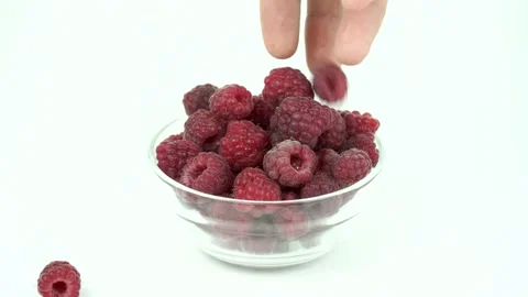 Put a fresh ripe raspberry in a glass transparent bowl on white background Video stock 133772246