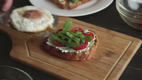Put fried egg on sandwich with  bread mashed avocado cherry tomatoes arugula Stock Footage 106874069