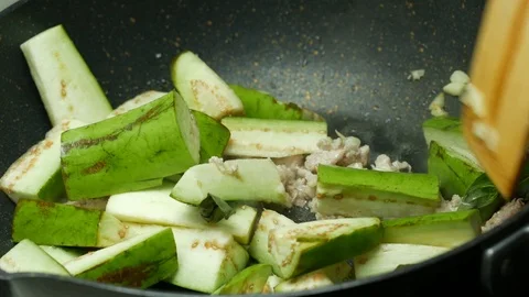 Put green sliced piece eggplants into the  pan ,  fried sliced garlic , food Stock Footage 89414939
