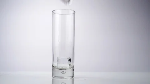 Put ice cubes in a glass an fill it up with Bitter Lemon Stock Footage 123422040