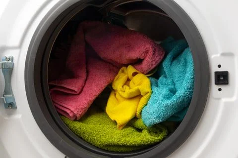 Put the laundry into the washing machine. focus on a colored towel. Stock Photos
