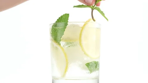 Put leaf of mint in glass with sparkling water, ice, lemon and mint Stock-Footage 134899333