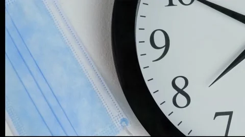 Put mask on table with clock after an hour the old mask is changed to a new one Stock Footage 162543498
