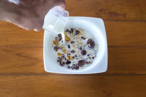 Put the milk into disk with many cornflake on wood table Stock Photos