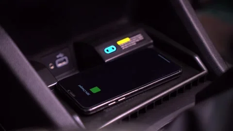Put the mobile phone for charging in wirless car charger Stock Footage 267564243