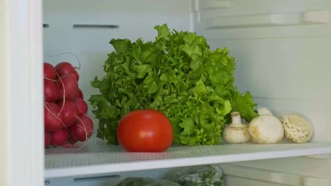 Put one tomato, pepper and cucumber into the fridge with lettuce, mushrooms and Stock Footage 144758605