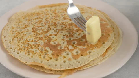 Put the pancake on a plate and grease with butter. Big round pancake. Cooking Stock Footage 146908349