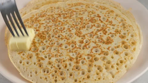 Put the pancake on a plate and grease with butter. Big round pancake. Cooking Stock Footage 146909250
