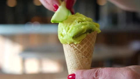 Put a piece of lime in a green ice cream in a cup woman with red manicure close Stock Footage 317716801
