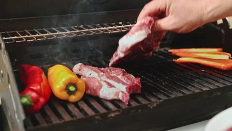 Put the raw meat on the hot grill, next to the sweet peppers and grilled carrots 스톡 동영상 198200588