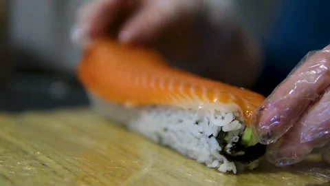 Put red fish on sushi chef puts red fish salmon on japanese sushi roll hands in Stock Footage 305986061