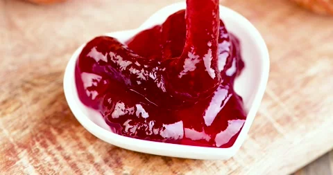 Put red strawberry jam on a white heart-shaped plate Stock Footage 195918969