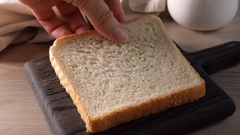 Put a slice of toast bread on a board for cook sandwich. Cooking breakfast in th Stock Footage 259462996