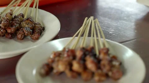 Put the sliced red onions on a white plate containing chicken satay Stock Footage 267681468