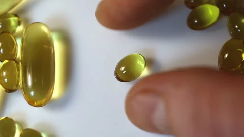 Put a small oval shiny transparent yellow capsule on the table. Real-time, close Stock Footage 145108204