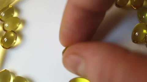 Put a small oval shiny transparent yellow capsule on a white background. Real-ti Stock Footage 145108394