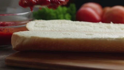 Put tomato sauce on loaf using spoon prepare sandwich close up Stock Footage 119801953
