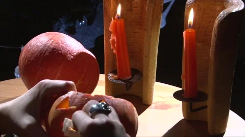 Put vampire teeth in Halloween pumpkin mouth, wooden table with candles Stock Footage 67897581