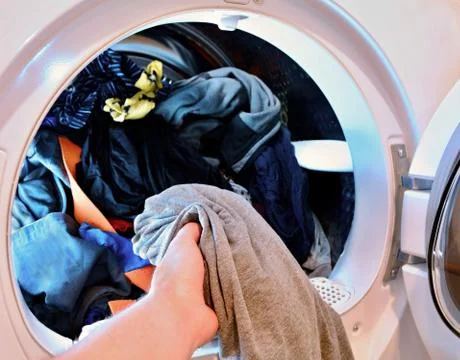 Put washed laundry into dryer. 스톡 사진