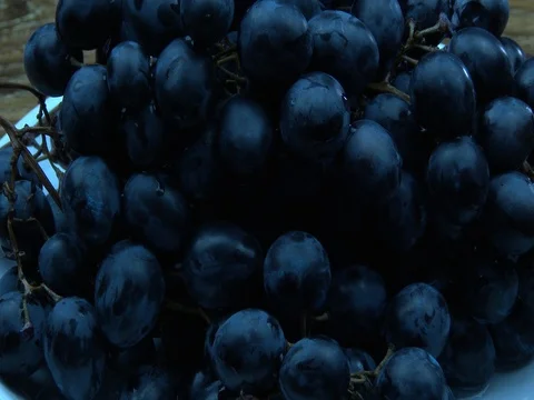 Put the white plate with black grapes on the table 스톡 동영상 80302574